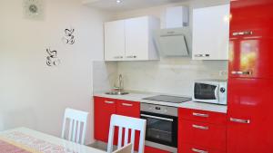 Kuchnia z czerwonymi szafkami i kuchenką mikrofalową w obiekcie Ferienhaus Holek w mieście Šilo +17 zdjęć