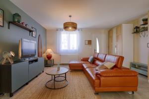 ein Wohnzimmer mit einem Ledersofa und einem TV in der Unterkunft La Dune Bleue / Maison 6 personnes à Houlgate in Houlgate + 26 Fotos