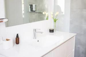 un bagno bianco con un vaso di fiori su un lavandino di 65onNorth ad Angaston