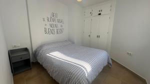 a small bedroom with a bed with a striped blanket at Mirador Playa in Conil de la Frontera