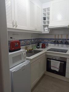 a small kitchen with white cabinets and a sink at Casa Rox in Villamartin