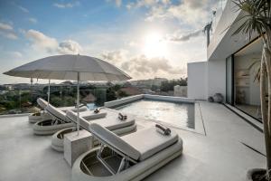 a pool with lounge chairs and an umbrella on a house at Luxury 4BD Villa with Oceanview in Uluwatu in Uluwatu