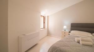 een witte slaapkamer met een bed en een raam bij Il Tuo Palazzetto in Castelsardo