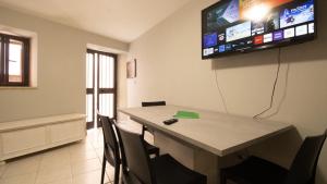 een kamer met een tafel met stoelen en een tv aan de muur bij Il Tuo Palazzetto in Castelsardo