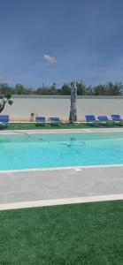 a swimming pool with blue chairs in front of a building at Villa La Gardenia in Marsala