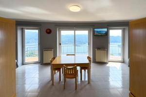 a dining room with a table and chairs and windows at Appartamento Alberti con vista lago in Madonna del Sasso