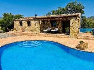 a swimming pool in front of a stone house at Poolhouse with private pool 360 degrees views over pure nature in Alozaina