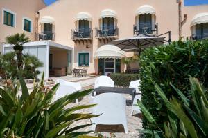 a group of white chairs in front of a building at Baglio Dello Zingaro in Scopello
