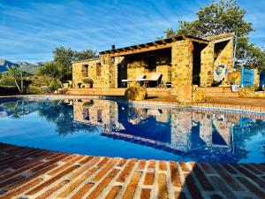 a stone house with a pool in front of it at Poolhouse with private pool 360 degrees views over pure nature in Alozaina