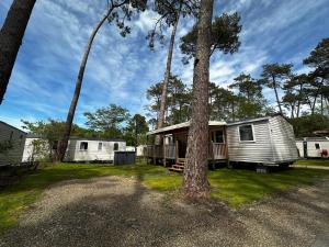 a white trailer with a porch and a tree at Grand Mobil Home Tout Confort pour 6 personnes - Camping Les Oyats 4 étoiles in Seignosse