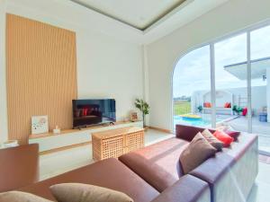 a living room with a couch and a large window at Santra Pool Villa in Pattani