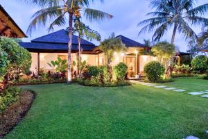a house with palm trees and a yard at Sakura 4 BR Private Pool Villa JU27 in Ketewel