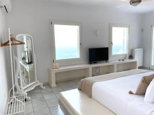 a white bedroom with a bed and a tv at Villa Artemis in Agios Georgios