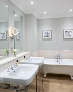a white bathroom with two sinks and a tub at Rookery Hall Hotel & Spa in Nantwich