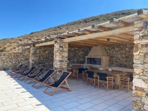 a patio with chairs and a table and a stone wall at Villa Artemis in Agios Georgios