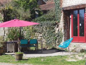 a table and chairs and an umbrella in front of a building at Chambre d’hôtes de Vauguenige in Saint-Pardoux