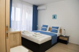 Un dormitorio con una cama azul y blanca y una ventana en Lux Sozopoli Hills Apartments A19 и Studio А13, en Sozopol