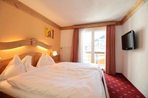 1 dormitorio con cama blanca y ventana en Hotel Christiania, en Saas-Fee