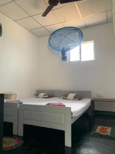 Cette chambre comprend un lit blanc et un parapluie bleu. dans l'établissement Flexi Lodge, à Negombo