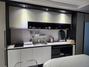 a kitchen with white cabinets and a sink and a bed at 다온# 동성로 스타비앤비 레지던스 in Daegu
