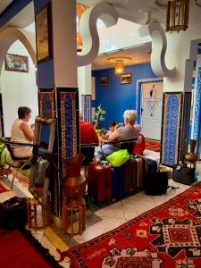 um grupo de pessoas sentadas numa sala com bagagem em Hôtel Riad Atlas Dades em Boumalne Dadès