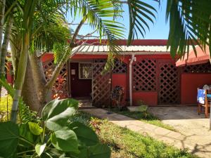 une maison rouge avec un palmier devant elle dans l'établissement Bungalow chez Mouch Nosy-Be 2, à Nosy Be