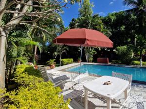 a table with a red umbrella next to a pool at Bungalow chez Mouch Nosy-Be 2 in Nosy Be