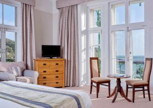 um quarto com uma cama, uma televisão e janelas em The Falmouth Hotel em Falmouth