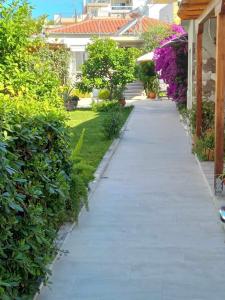 un vialetto in un cortile con cespugli e fiori di Alkistis House a Volos