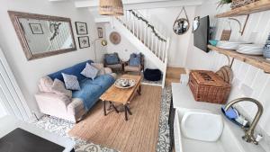 sala de estar con sofá azul y mesa en AMAZING LOCATION - "SMUGGLERS HIDE" & "SMUGGLERS CABIN" - a 2 BEDROOM FISHERMANS COTTAGE with HARBOUR VIEW and also a private entrance 1 BED STUDIO - 10 Metres To Sea Front - BOOK BOTH for ENTIRE 3 BEDROOM COTTAGE - 2023 GLOBAL REFURBISHMENT AWARD WINNER, en St Ives