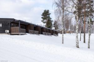 a log cabin in the snow with trees at Ellivuori Chalet in Sastamala