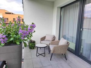 a balcony with two chairs and a table and flowers at Tabáň Marble apartment (city center & free parking) in Nitra +21 photos