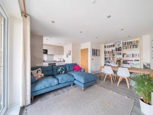 een woonkamer met een blauwe bank en een keuken bij Pass the Keys Bright modern flat wparking in Addlestone
