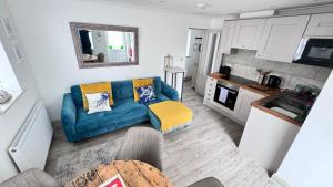 un soggiorno con divano blu e una cucina di ABOVE ST IVES PORTHMINSTER BEACH - "St James Rest" is a REFURBISHED & SUPER STYLISH PRIVATE APARTMENT - King Bedroom with Ensuite, Family Bathroom, Double Bunk Cabin & Sofabed LoungeKitchenDiner - 2 mins walk Main Car Park & Station a St Ives