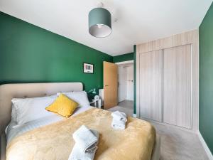 een slaapkamer met een bed met een groene muur bij Pass the Keys Bright modern flat wparking in Addlestone