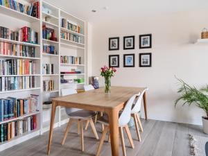 a dining room with a wooden table and white bookshelves at Spacious Apartment in Addlestone with Free Parking- Pass the Keys in Addlestone