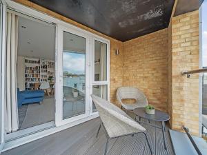 een veranda met stoelen, een tafel en glazen deuren bij Pass the Keys Bright modern flat wparking in Addlestone