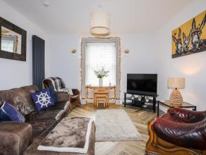 a living room with leather furniture and a flat screen tv at Brigwyn in Pwllheli