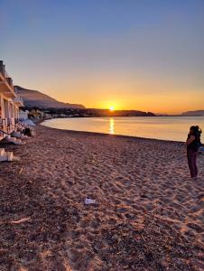 a woman walking on the beach at sunset at SantOliva Apartments in Trabia