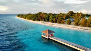 an island in the ocean with two people sitting on a dock at Sabba Summer Suite , Fodhdhoo in Fodhdhoo