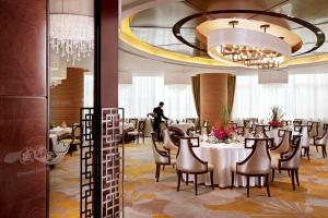 un comedor con mesa, sillas y un hombre en Lake View Hotel, en Beijing
