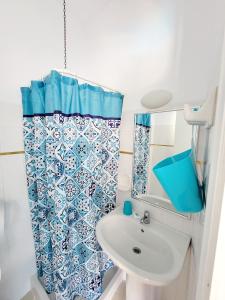 a bathroom with a blue and white shower curtain and a sink at Kalimera Studios and Apartments in Moraitika