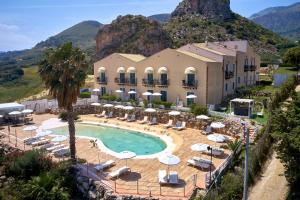 ein Resort mit einem Pool mit Stühlen und Sonnenschirmen in der Unterkunft Baglio Dello Zingaro in Scopello