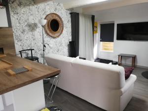een woonkamer met een witte bank en een tafel bij Charmante longère en pierres refaite à neuf in Moëlan-sur-Mer