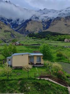 a house in a field with mountains in the background at Mountain KAZBEGI Apartment in Kazbegi