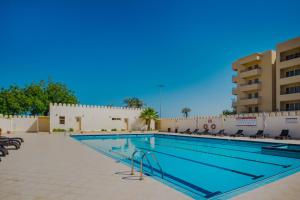 a large swimming pool with chairs and a building at Live surrounded by gorgeous Green Golf fields in Ras al Khaimah
