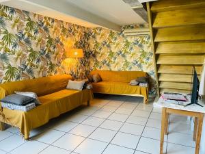 a living room with two yellow couches and a tv at La Bastide des Songes - Demeure d'hôtes in Robion en Luberon