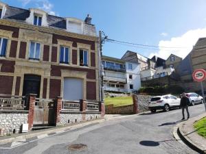 a man walking down a street next to a brick building at L'HORIZON Vue mer et falaises in Fécamp