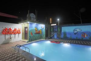 奥拉奇哈Bundeli Farm Resort & Banquet Orchha的游泳池晚上墙上挂着一幅画