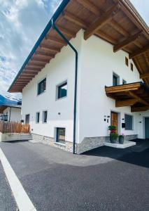 un grand bâtiment blanc avec un toit en bois dans l'établissement Apart Helena, à Mayrhofen